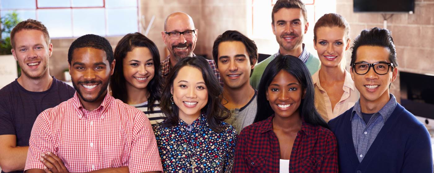 A group of ten colleagues in a bright office, smiling at the camera